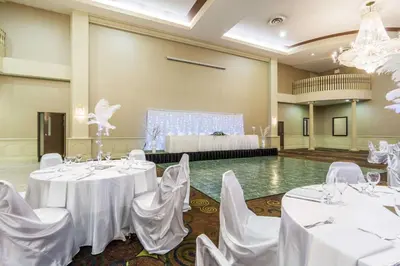 a banquet hall with white tables and chairs and a stage at Clarion Hotel & Conference Centre in Sherwood Park