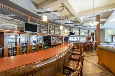 a bar in a restaurant with wooden tables and chairs at Clarion Hotel & Conference Centre in Sherwood Park