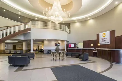 a lobby with a table and chairs and a staircase at Clarion Hotel & Conference Centre in Sherwood Park
