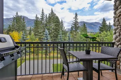 a balcony with a table and chairs and a grill at The Mountaineer by InstantSuites Pool & HotTub in Canmore