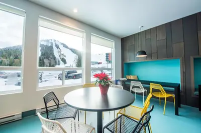 a dining room with a table and chairs and windows at Nowhere Special Hostel in Rossland