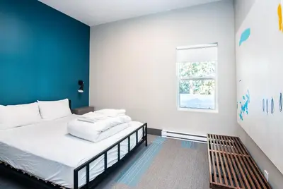 a bedroom with a bed with a blue wall at Nowhere Special Hostel in Rossland