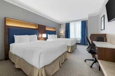 a hotel room with two beds and a desk at Best Western Plus Revelstoke in Revelstoke