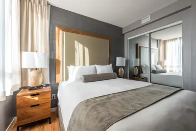 a bedroom with a large bed and a large mirror at Carmana Hotel & Suites in Vancouver