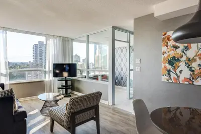 a living room with a table and chairs and a television at Carmana Hotel & Suites in Vancouver