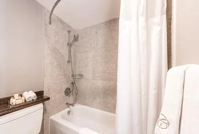 a bathroom with a shower and a white tub at Carmana Hotel & Suites in Vancouver