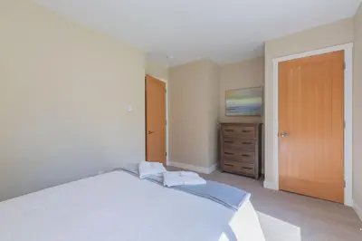 a bedroom with a white bed and a wooden door at Mayne Island Resort in Mayne Island