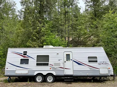 a white trailer parked in front of a forest at Noah's Ark Campground in Revelstoke