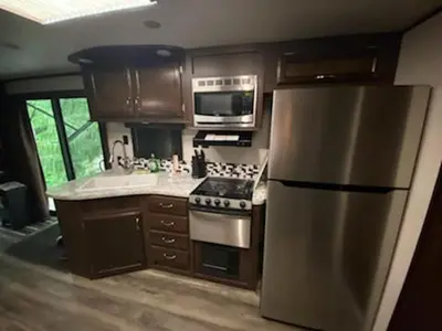 a kitchen with a stainless steel refrigerator and microwave at Noah's Ark Campground in Revelstoke