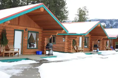 a log cabin with a porch in the snow at Twin Peaks Resort in Valemount