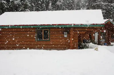 a log cabin with a dog in the snow at Twin Peaks Resort in Valemount