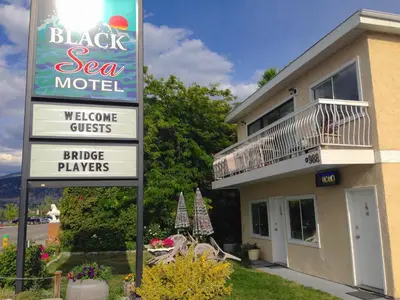 a sign for a black sea motel with a building at Black Sea Motel in Penticton