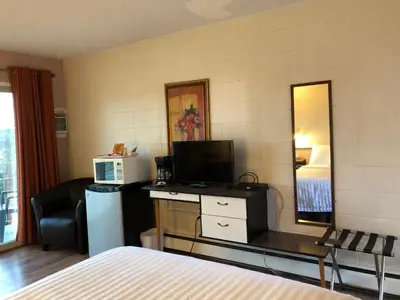 a hotel room with a bed and a desk with a mirror at Holiday House Motel in Ladysmith