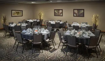 a group of tables and chairs in a room at Neighbourhood Inn Hotels in Bonnyville in Bonnyville