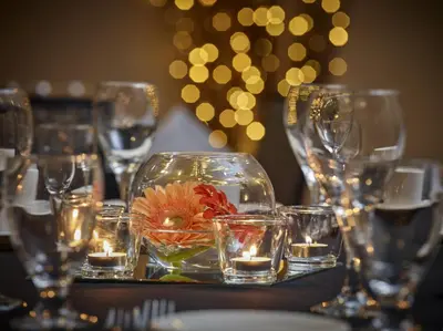 a table with glasses and a bowl with a flower in it at Neighbourhood Inn Hotels in Bonnyville in Bonnyville