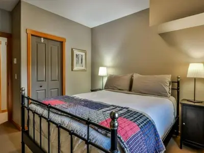 a bedroom with a large bed with a blanket at Suites with Pool & Hot tubs managed by Little Sister Getaways in Canmore