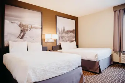 a hotel room with two beds and a painting on the wall at Super 8 by Wyndham Revelstoke BC in Revelstoke