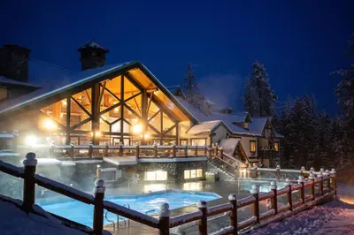 a house with a pool in the snow at night at Lizard Creek Lodge in Fernie