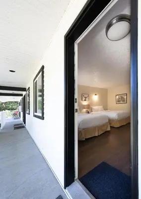 a room with two beds and a bedroom with a window at West Coast Trail Lodge in Port Renfrew