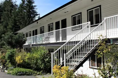 a building with a white staircase next to it at West Coast Trail Lodge in Port Renfrew