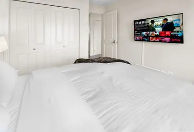 a white bed in a bedroom with a tv on the wall at 5 STAR Business Luxury Homeshare in Edmonton