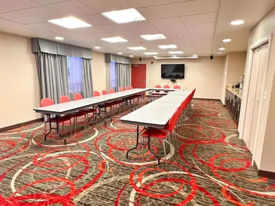 a conference room with long tables and red chairs at Chateau Inn & Suites Bonnyville in Bonnyville