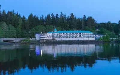 a large building with a blue roof on the water at Glen Lyon Inn in Port Hardy