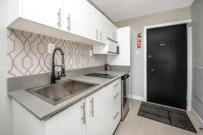 a kitchen with a sink and white cabinets at Sea Edge Beachside Hotel in Parksville