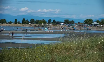 a crowd of people on a beach with water at Sea Edge Beachside Hotel in Parksville