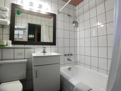 a bathroom with a tub and a toilet and a sink at Alpine Inn & Suites in Revelstoke