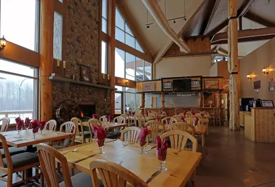 a restaurant with wooden tables and chairs with red flowers on them at Fernie Stanford Resort in Fernie