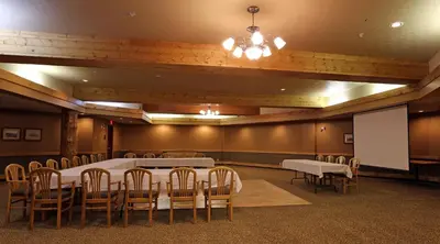 a conference room with a table and chairs and a screen at Fernie Stanford Resort in Fernie