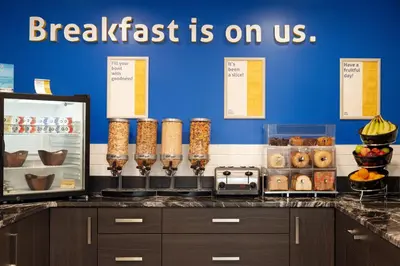 a breakfast is on us sign on a counter with food at Days Inn by Wyndham Wainwright in Wainwright