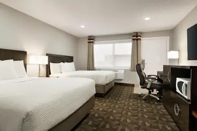 a hotel room with two beds and a desk at Days Inn by Wyndham Wainwright in Wainwright