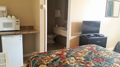 a room with a bed and a kitchen with a microwave at Viking Lamplighter Motel in Viking