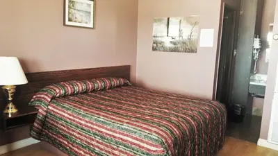 a hotel room with a bed with a striped blanket at Viking Lamplighter Motel in Viking