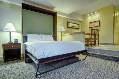 a bedroom with a large bed and a dining room at Mountain Side Hotel Whistler by Executive in Whistler