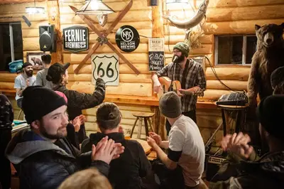 a man standing in a room with a group of people at The Raging Elk Adventure Lodging in Fernie