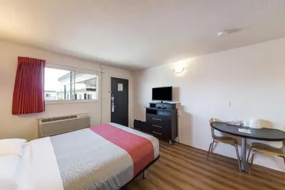 a hotel room with a bed and a desk and a window at Motel 6-Cranbrook, BC in Cranbrook