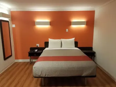 a bedroom with a bed with an orange wall at Motel 6-Cranbrook, BC in Cranbrook