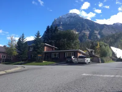 a house with a mountain in the background with cars parked on the street at Canadian Rockies Inn - Adults only in Field