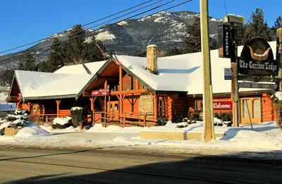 a log cabin with snow on the roof at Cariboo Lodge in Clinton