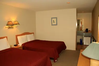 a hotel room with two beds and a lamp at Cariboo Lodge in Clinton