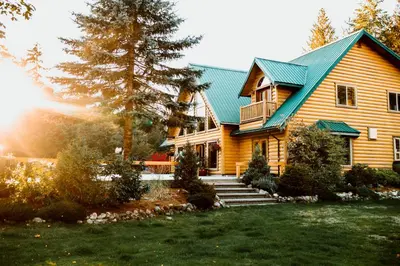 a large wooden house with a green roof at Cowichan River Lodge in Lake Cowichan