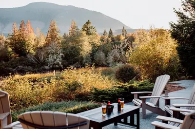 a patio with chairs and a table with drinks on it at Cowichan River Lodge in Lake Cowichan