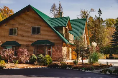 a wooden house with a green roof at Cowichan River Lodge in Lake Cowichan