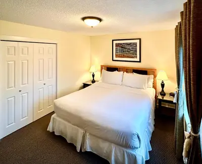a bedroom with a large white bed and two lamps at Bayshore Waterfront Inn in Ucluelet