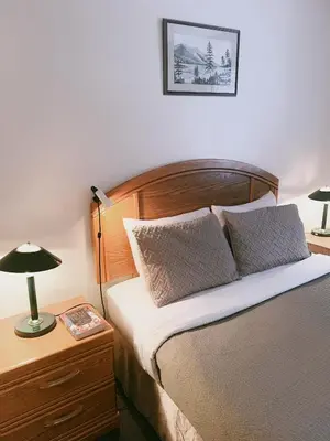 a bedroom with a bed and a table with a lamp at Alpine Meadows Lodge in Golden
