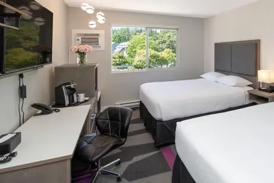 a hotel room with two beds and a desk at The Spot at Porpoise Bay in Sechelt