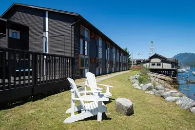 two white chairs sitting on the grass in front of a building at The Spot at Porpoise Bay in Sechelt